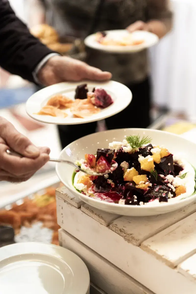 Gast schöpft Randensalat mit Feta und Orangen am Buffet des edison Kultursalon